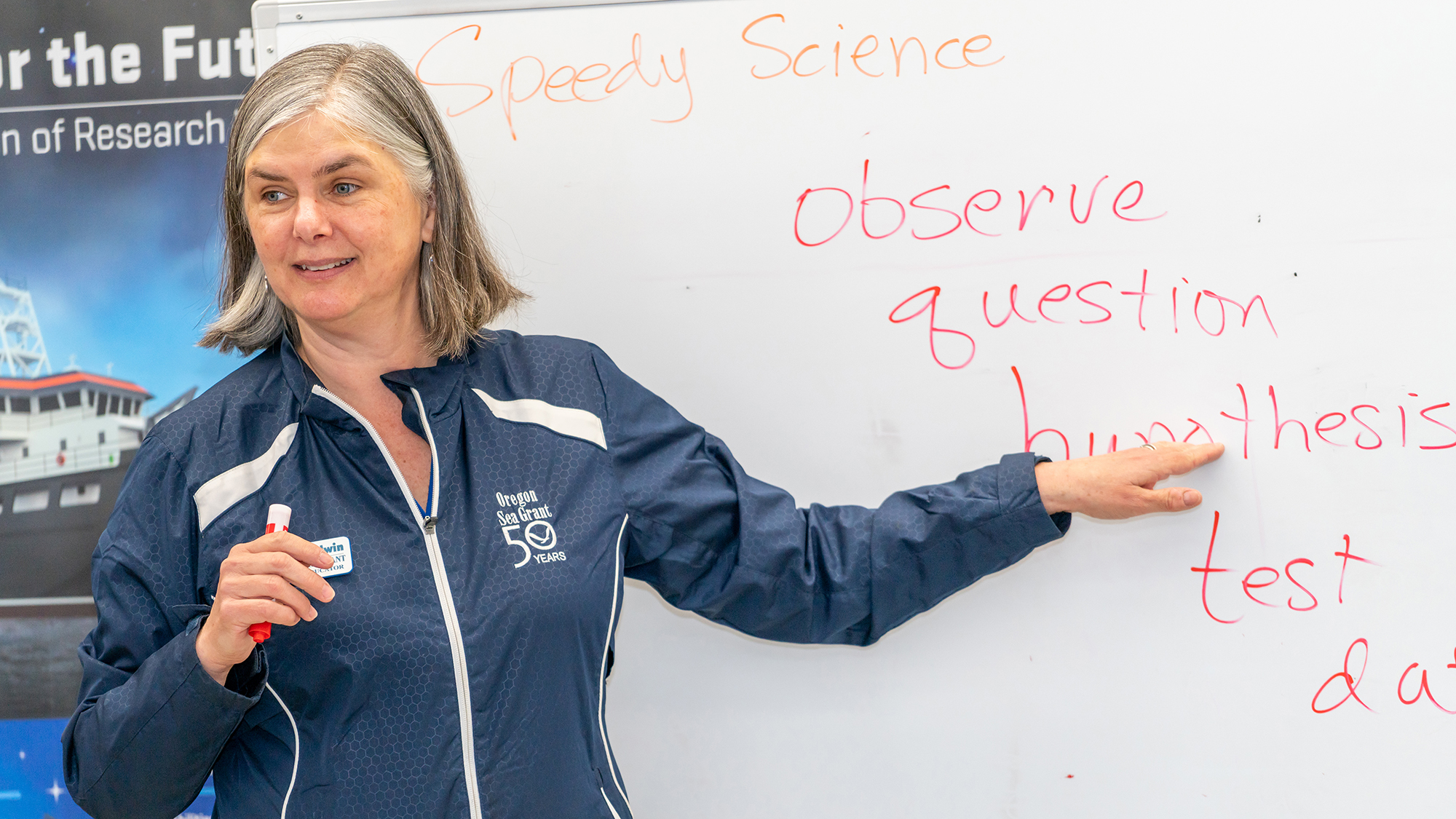 Woman with Sea Grant jacket on pointing to whiteboard
