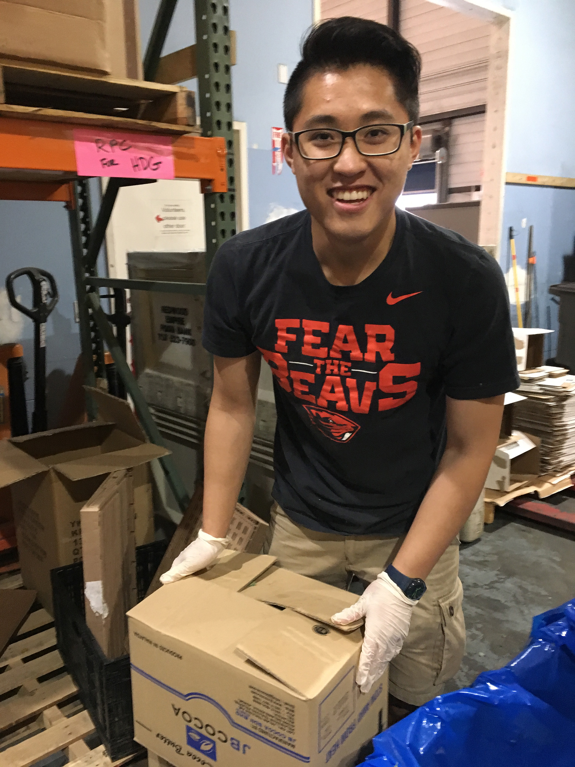 Student packing up food in a box in a warehouse