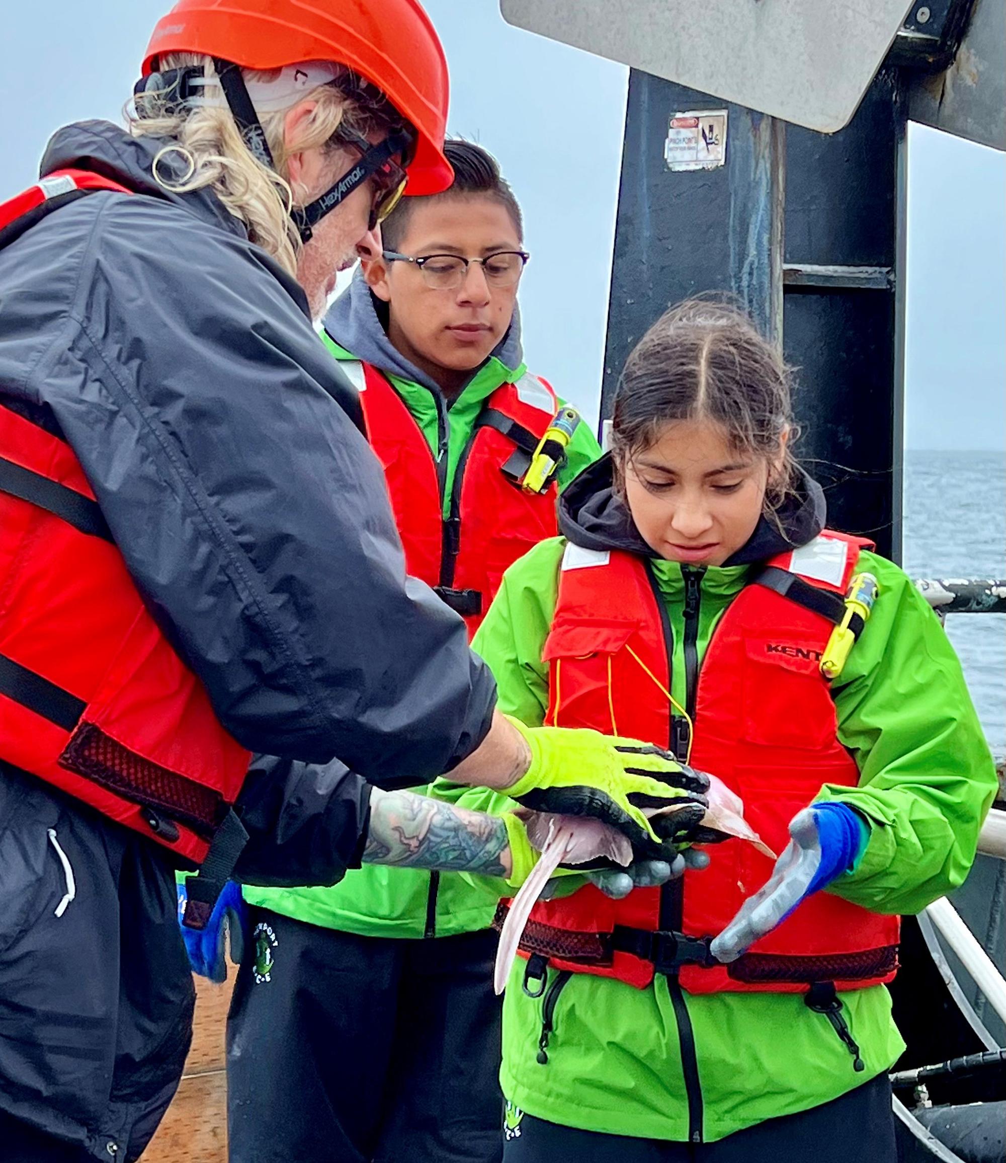 people in life jackets teaching a youth about marine life
