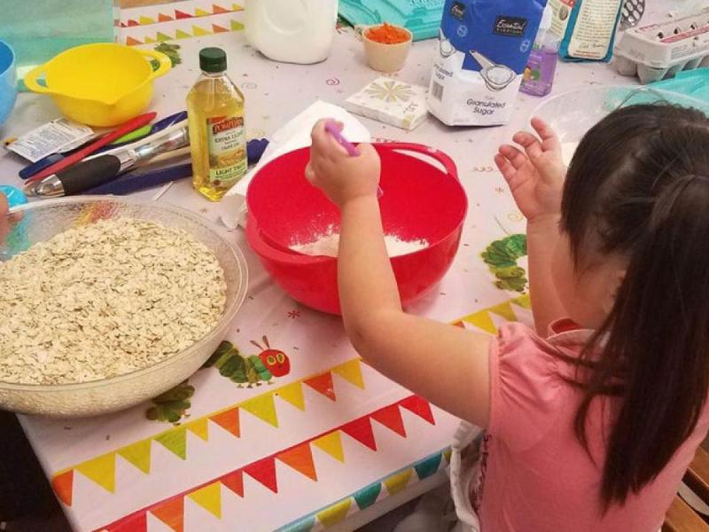 young girl works on recipe in a bowl