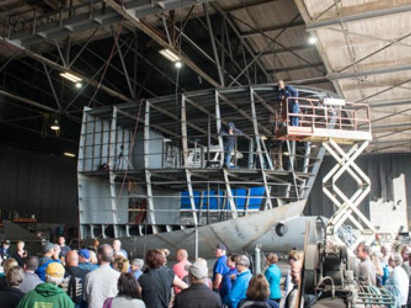 crowd looking up at ship being built in a tall hangar