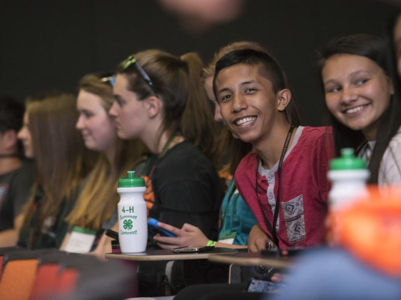 Youth smiling in row of seats with 4-H water bottles